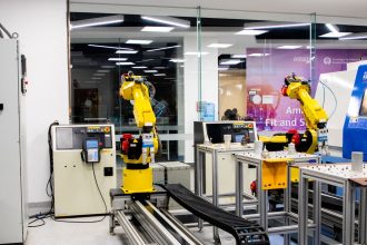 Braços robóticos operam em um ambiente industrial moderno de controle e produção.