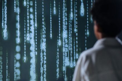 Pessoa observando números iluminados em uma tela, em uma representação de tecnologia e análise de dados.